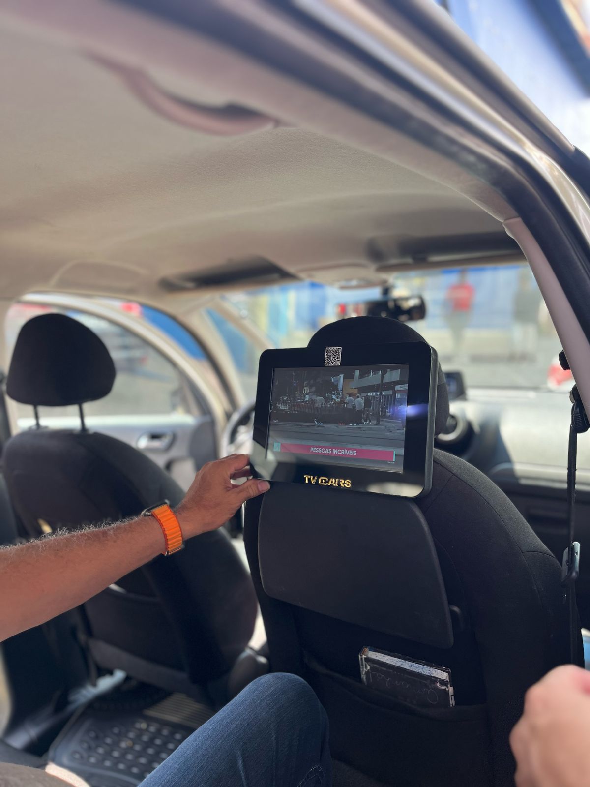 Motorista ajustando a TV Cars no encosto enquanto exibe conteúdo aos passageiros